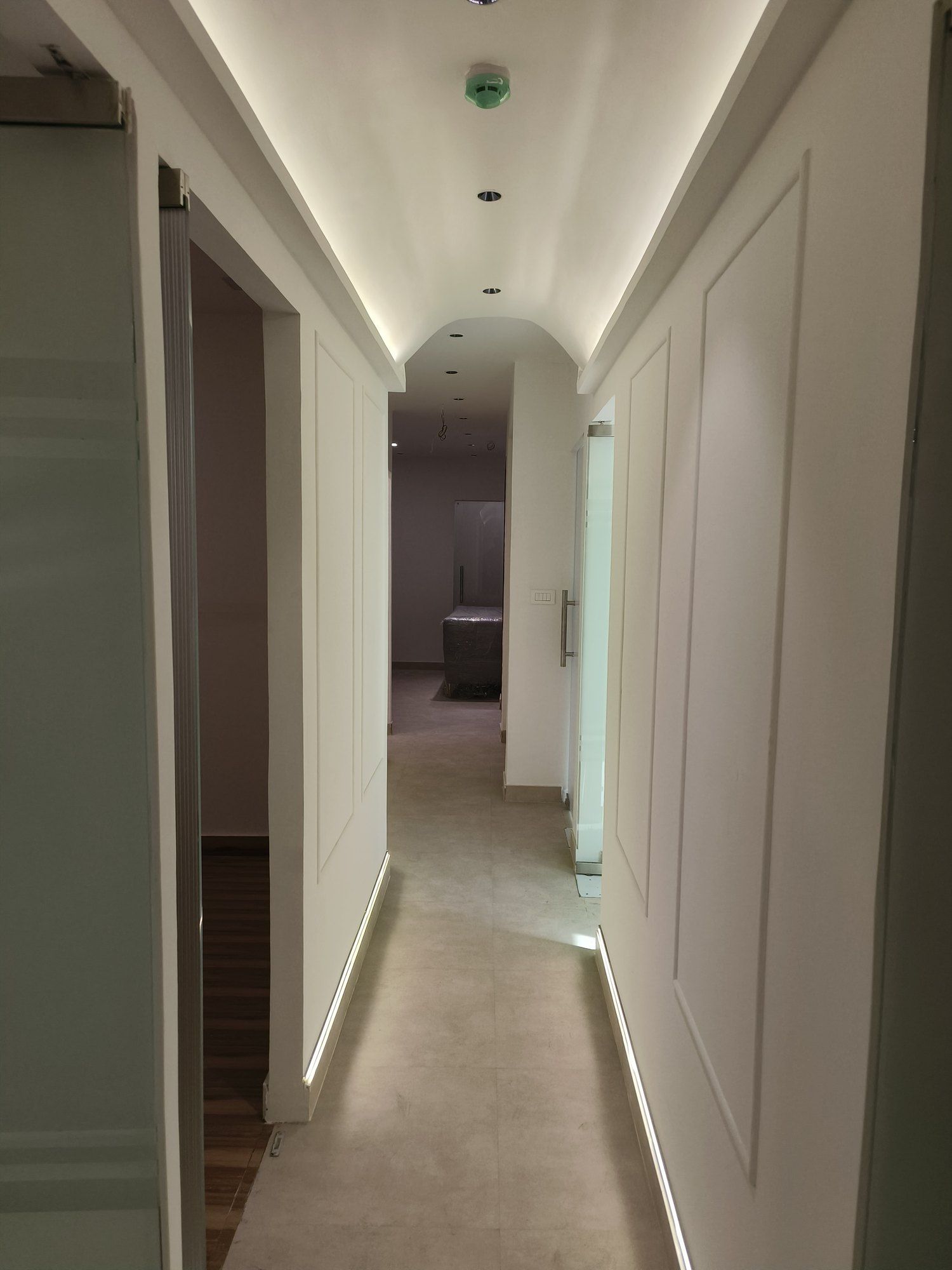 Corridor at New World Fertility Centre with a vaulted ceiling lit by cove lighting, panelled walls and LED strips along the skirting