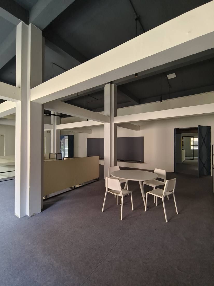 Double-height workspace at IILM University with exposed white beams and meeting tables