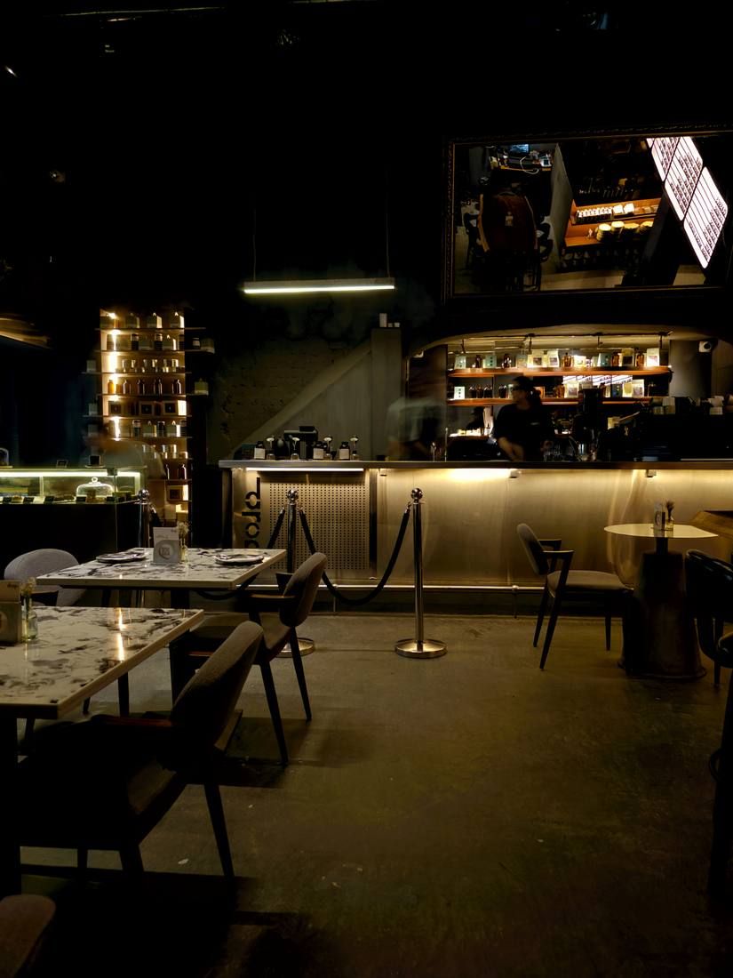 The bar at The Drop, lit low against dark walls, with tables in the foreground