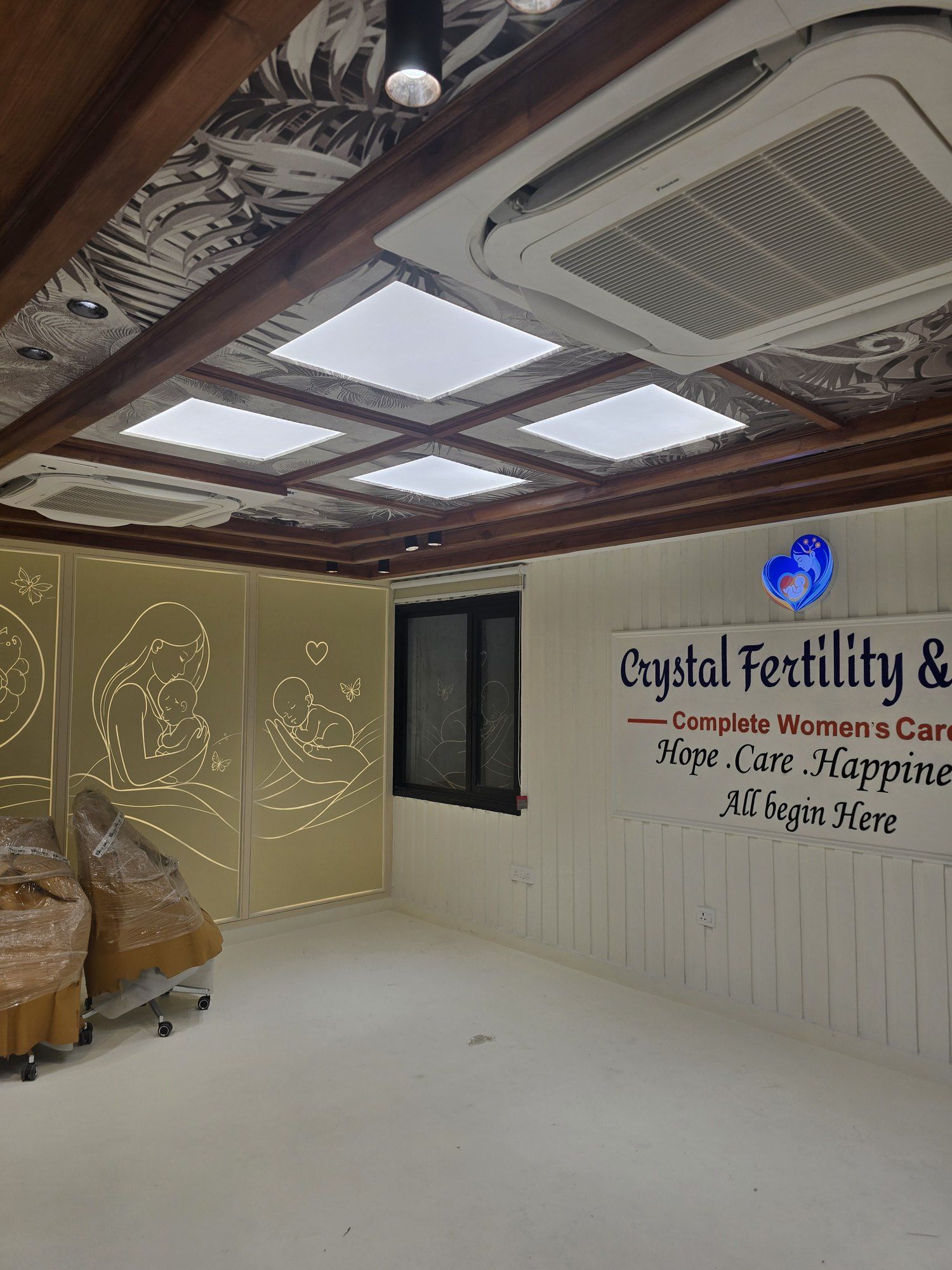 Waiting area at Crystal IVF with a timber coffered ceiling, backlit ceiling panels and line drawings of mother and child