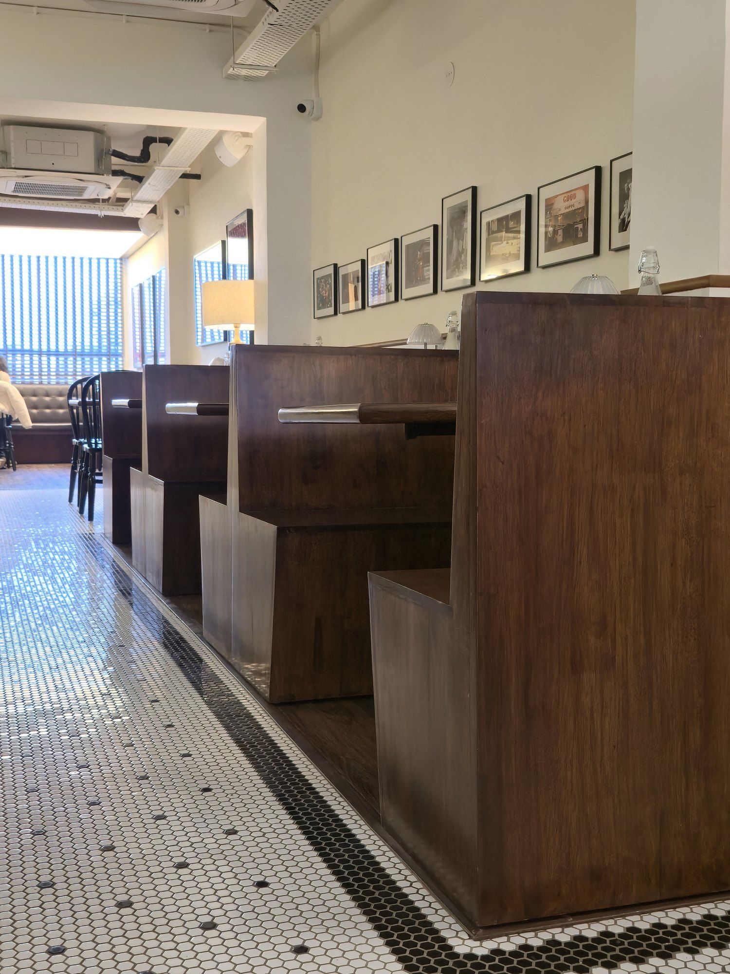 Dark wood booths along a black and white penny tile floor at Galaxy Slice Shop