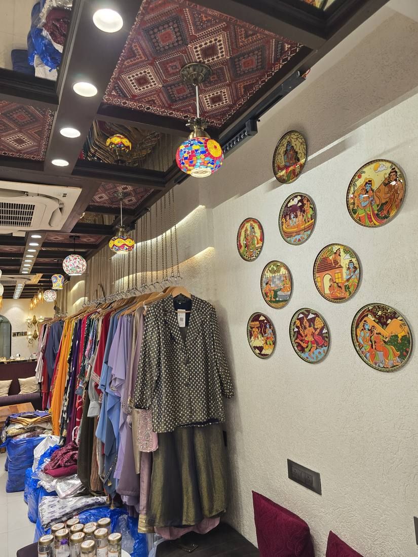 Gallery wall of hand-painted Pichwai plates beside clothing racks
