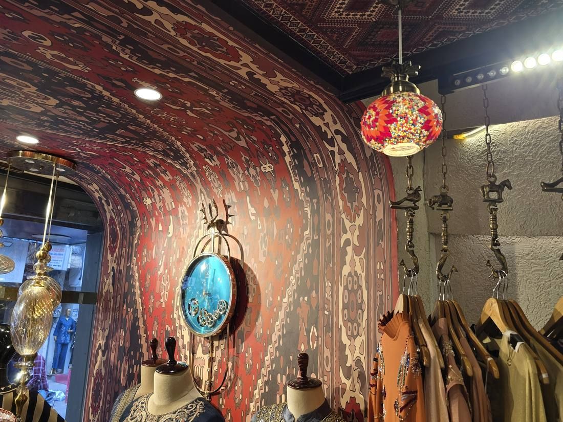 Carpet-pattern wall and ceiling with a mosaic lamp and ethnic wear on display