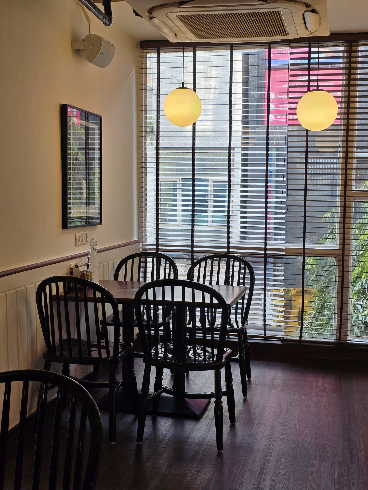 Window seating with black spindle-back chairs under globe pendant lights