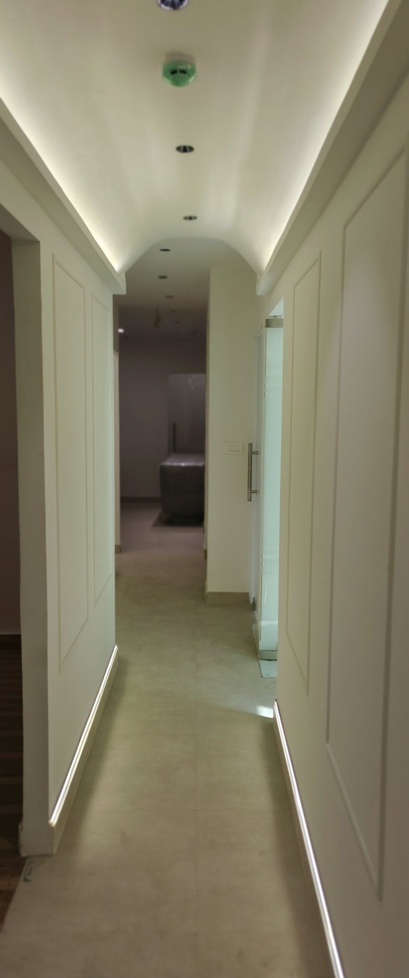 Corridor with glass doors, moulded wall panels and light along the edges of the ceiling