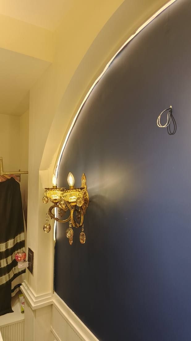 Navy arched wall with a brass wall sconce