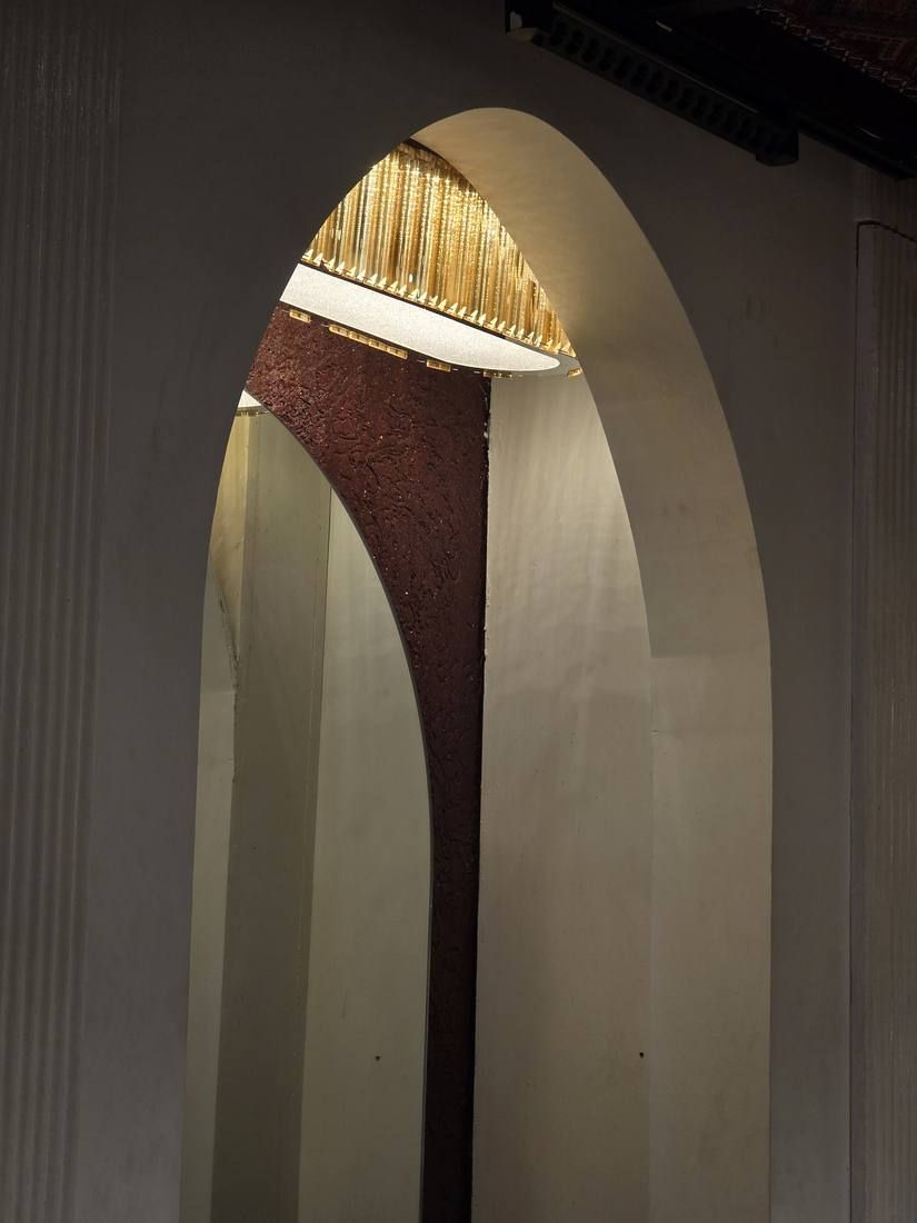 Arched opening with a draped curtain and a lamp above