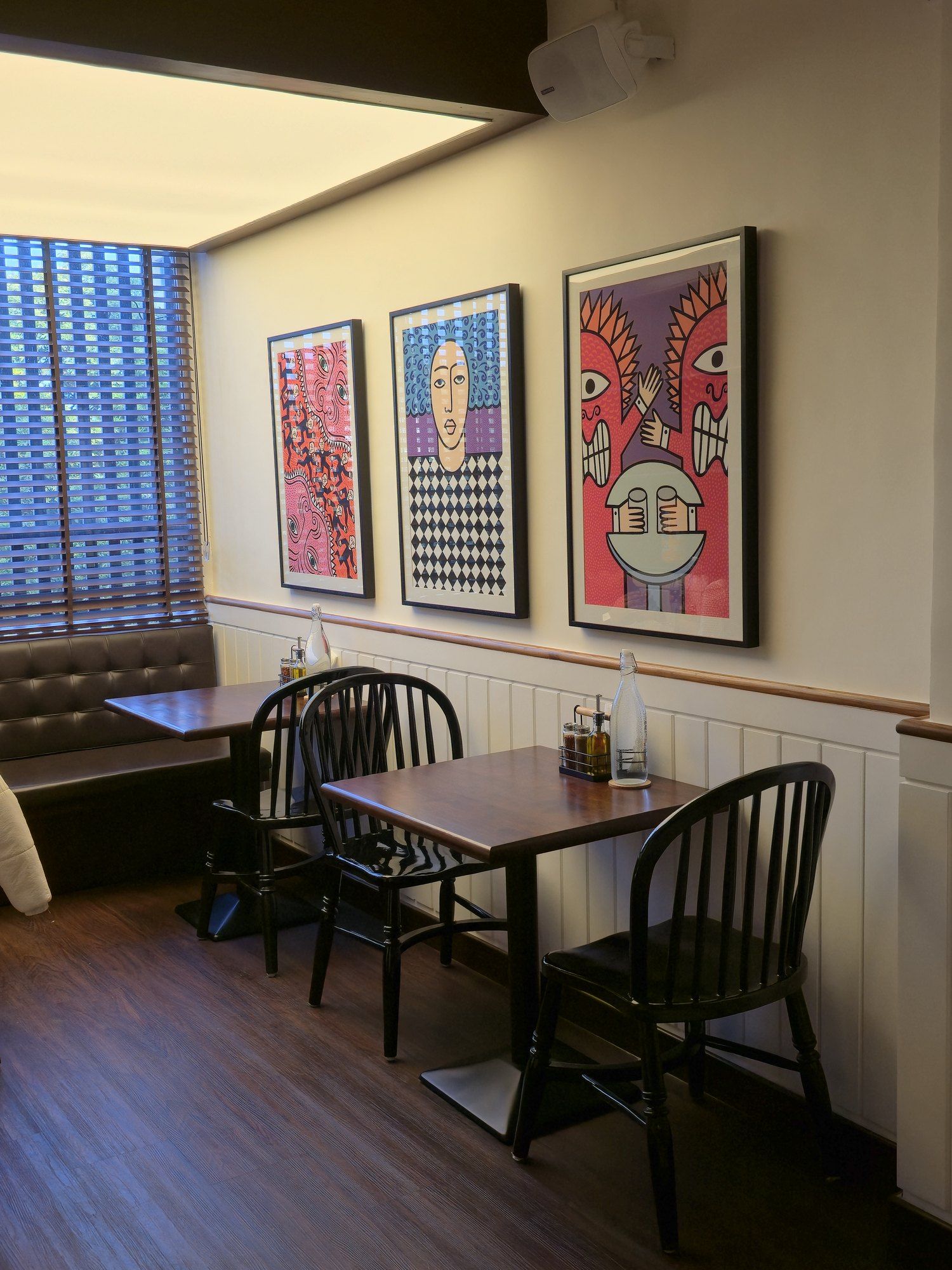 Corner table beneath three pop-art prints at Galaxy Slice Shop