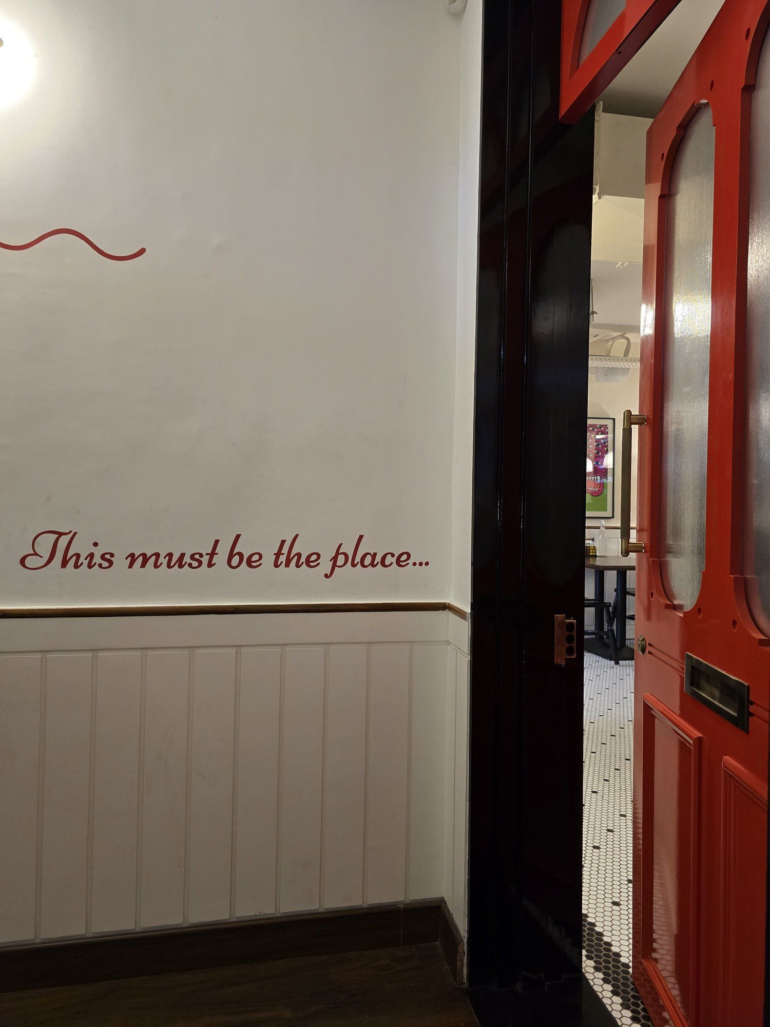 Hand-lettered wall text reading This must be the place, beside a red door